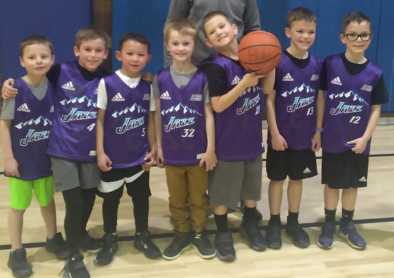 Eight boys posing in purple jerseys with a basketball